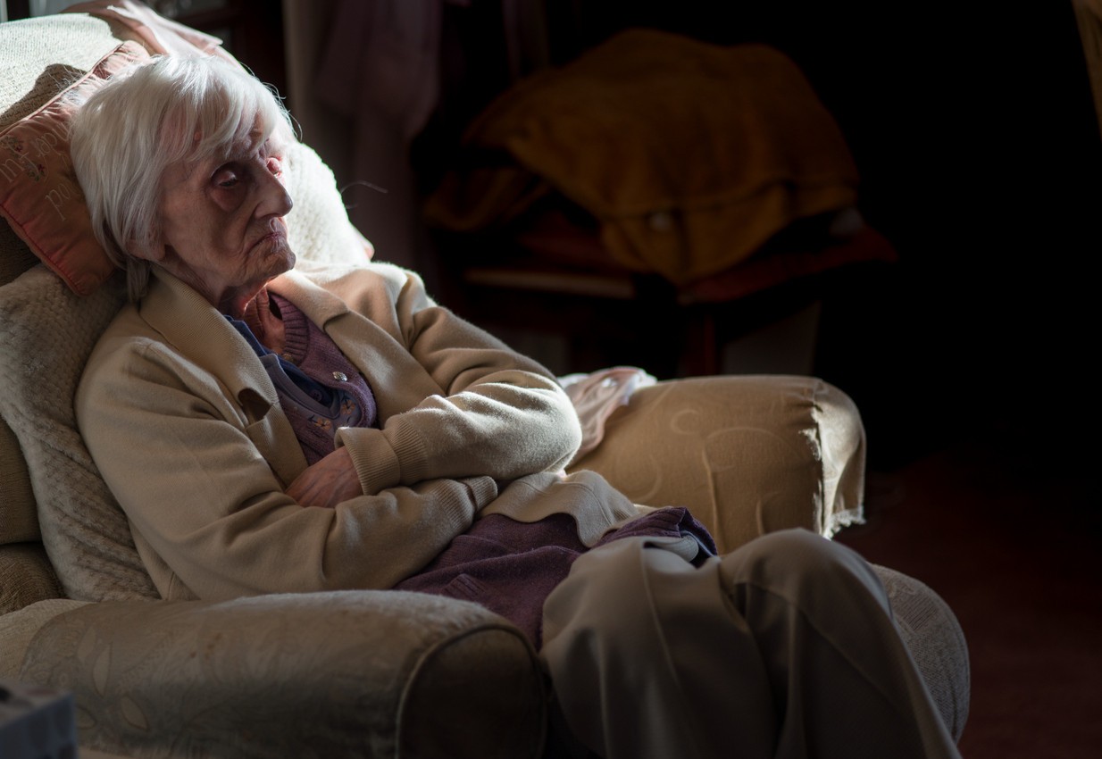 An older woman sat alone in a darkened room