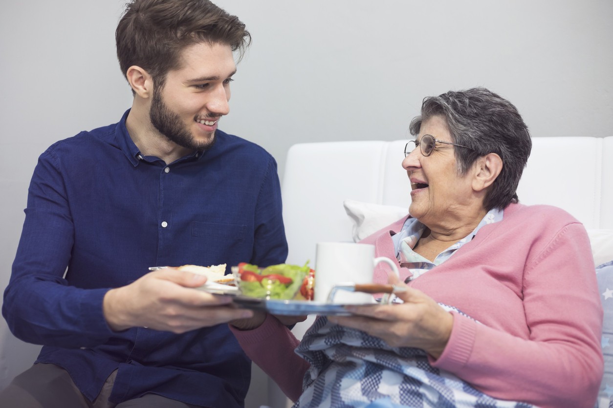 A care worker handing over a meal to an older woman