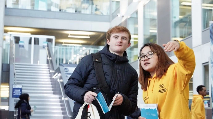Volunteer giving directions to prospective student at an open day