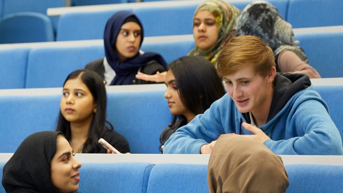 A group of first generation students chatting in a lecture theatre