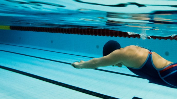 A swimmer holds a toe rig system while submerged in a swimming pool