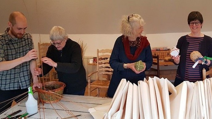 Four researchers collaborating on basket weaving