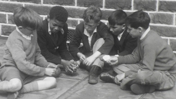 Boys sat on the pavement playing cards in the 1950s