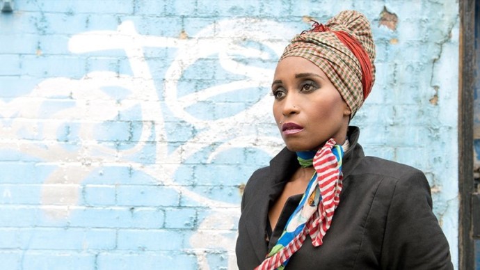 Poetry writing prize winner Malika against a brick wall with graffiti