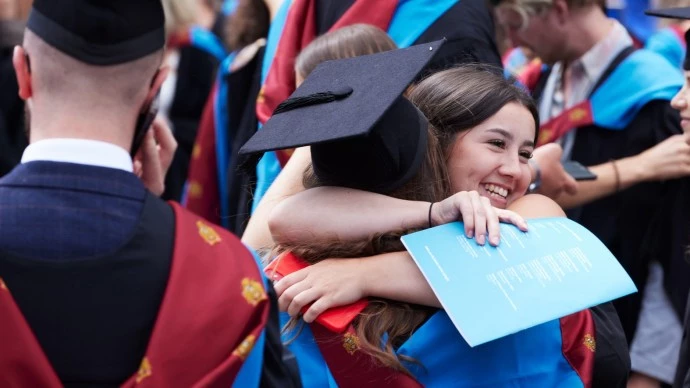 Two graduates hugging at their graduation ceremony