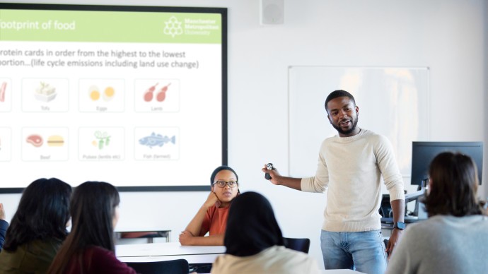 A tutor stood in front of a white board delivering Carbon Literacy training to a group of students