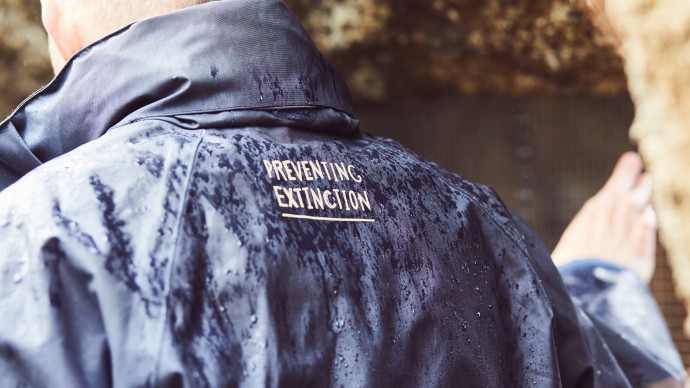 Zoo staff stood in a cave wearing a coat that says 'Preventing Extinction'