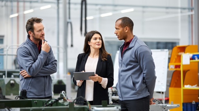 Three people in discussion on a factory floor