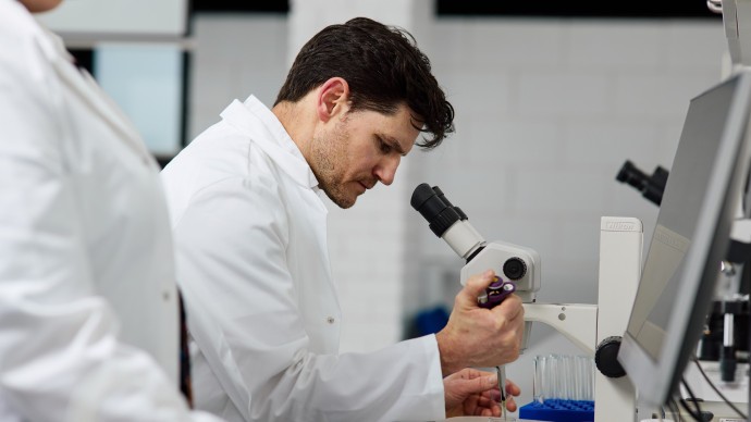 Dr Michael Carroll using a pipette and petri dish to do a sample analysis using the microscope 