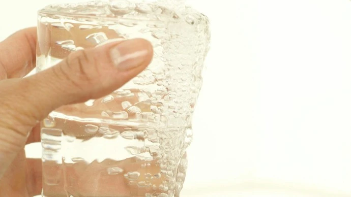 Water coming out of a tap going into a glass being held by a hand