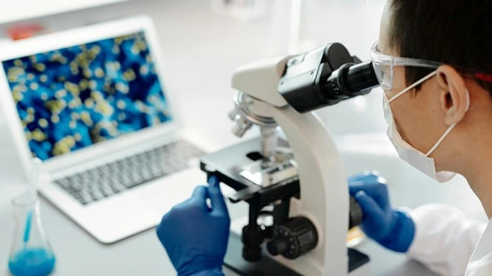 Scientist looking into a microscope in a lab setting