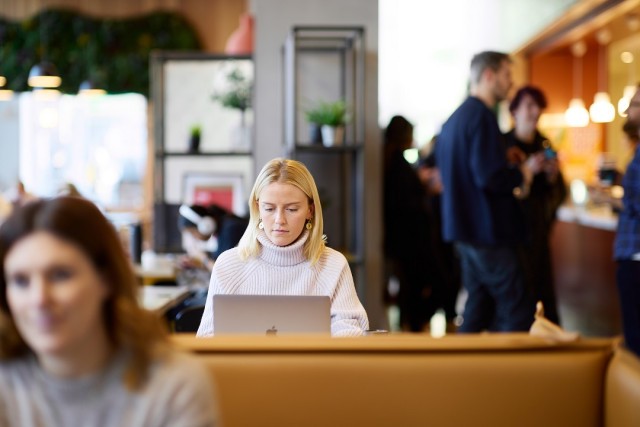 Graduate on laptop in a busy café