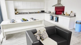 The archway lounge and kitchen area which is open plan and features a stove and oven, a table and seating area and a small sofa.