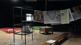 an installation of school furniture, draped paper prints and a projection