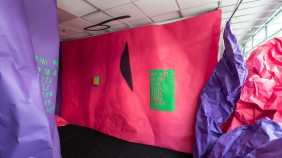 Installation which includes creating a partitioned space using 11 meter by 2.75 meter sheets of bright pink and purple, recycled paper and a series of moulded sculptural works including hill-like structures, appearing to drip from the window, or pour out of the walls. Bright pink and purple sheets of scrumpled paper are piled up hight against the window in layers - they look a bit like sedimentary rock formations. 