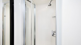 A shower cubicle in a white room with chrome fixtures and fittings