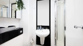 An ensuite bathroom with shower cubicle, sink, mirror and toilet