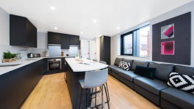 A kitchen with breakfast bar, two cookers, sink and four sofas