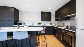 A kitchen in a student flat with two cookers, sinks, fridge freezer and dining table
