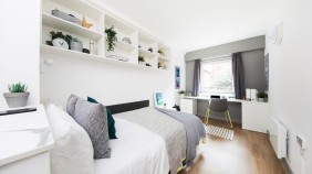 A study bedroom with shelving, a desk and storage cupboards
