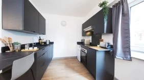 A student kitchen with cooker, sink, food preparation space and a breakfast bar