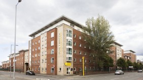 Brook Hall viewed from across the road, a six-storey apartment building on a tree-lined street