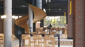 The House of Social entrance, with a wood spiral staircase surrounded by dining tables and chairs