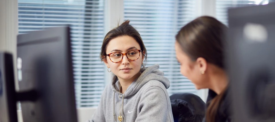 Students talking sat in front of computers