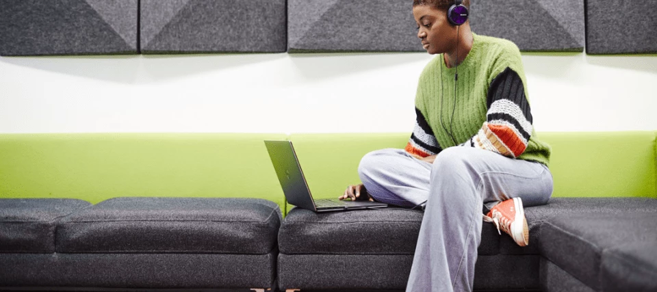 A student sat down on their laptop with headphones on