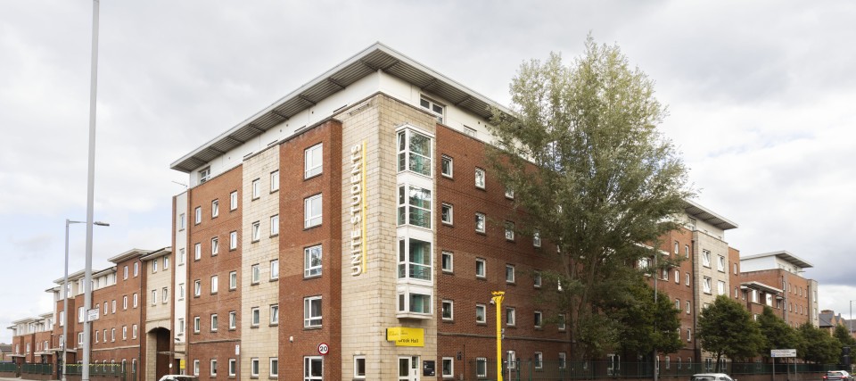 Brook Hall viewed from across the road, a six-storey apartment building on a tree-lined street