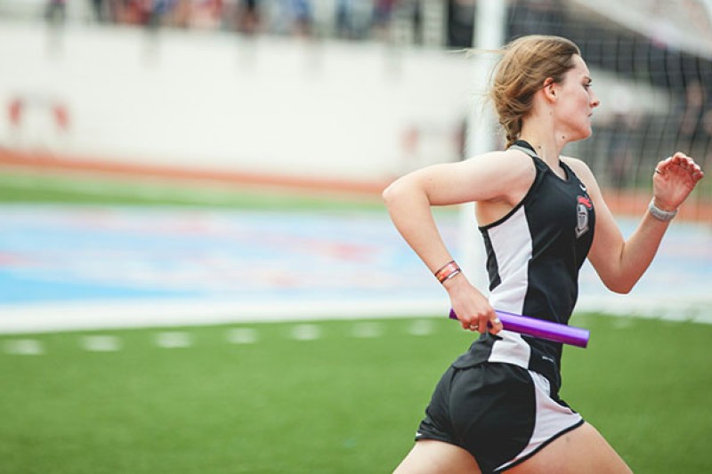 A female athlete runs carrying a baton
